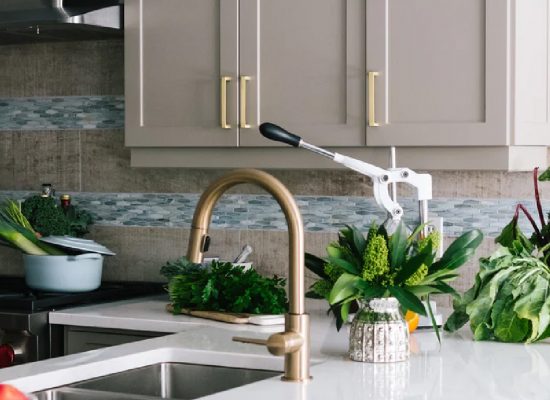 a bespoke kitchen by Vision Kitchens and Interiors with cream cabinets, sink, tap and indoor flowers